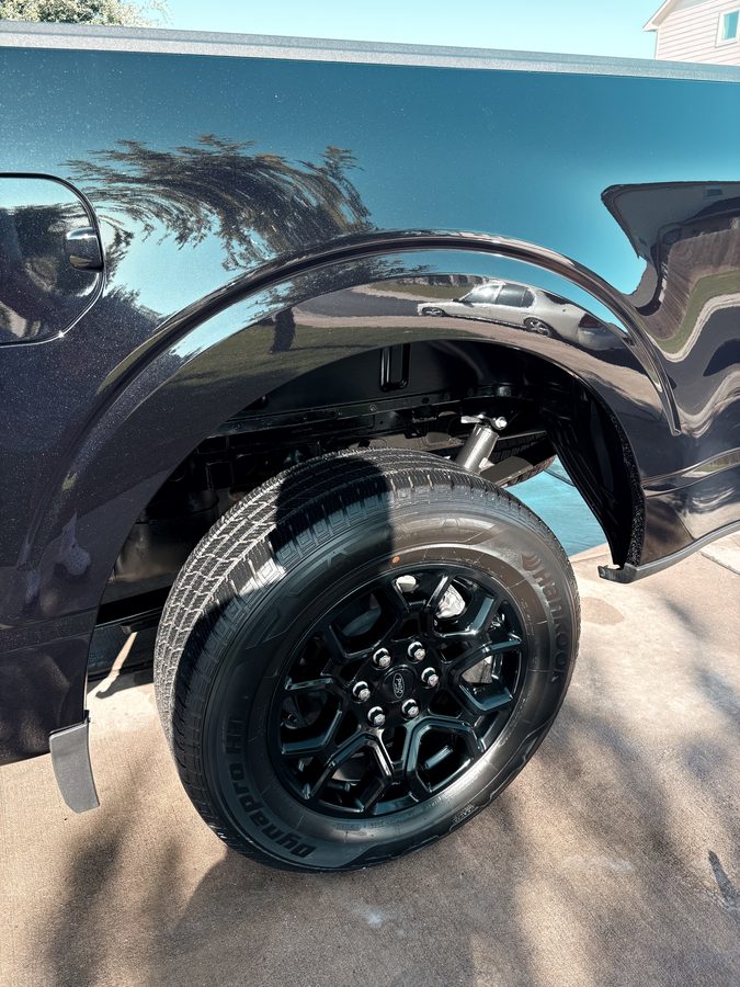 Glossy black Ford F-150 rear quarter panel and wheel after an exterior detail
